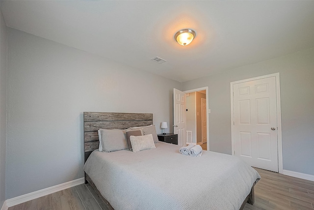 bedroom featuring visible vents, baseboards, and wood finished floors