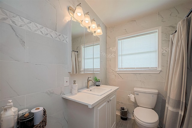 bathroom with toilet, curtained shower, vanity, and tile walls