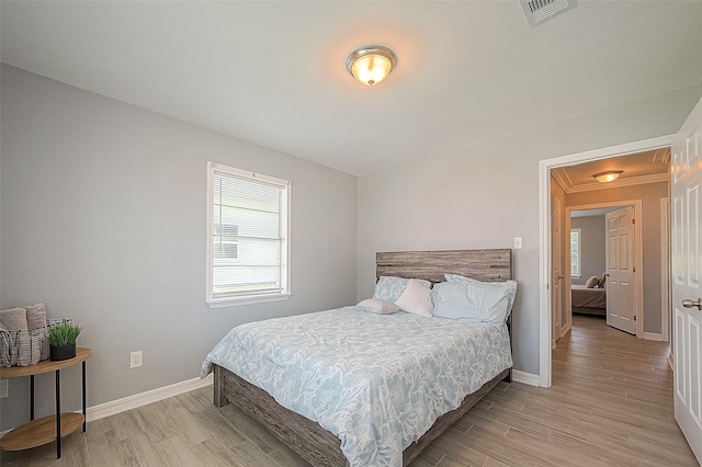 bedroom featuring light wood-style flooring, visible vents, and baseboards