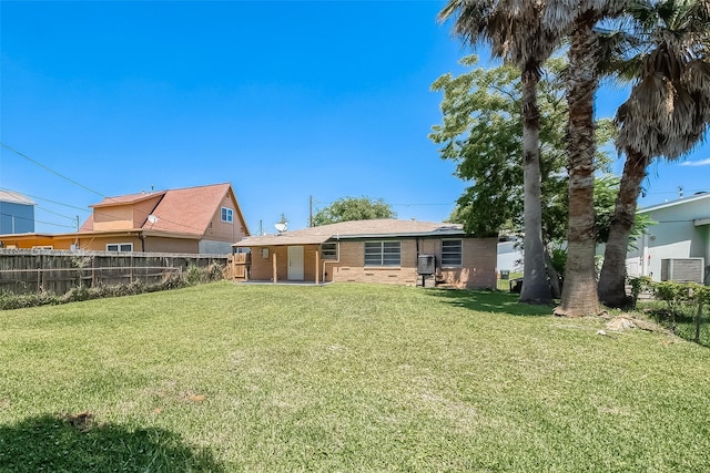 rear view of property with brick siding, a lawn, and fence