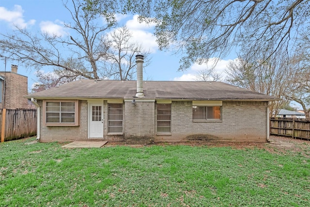 back of house with a yard, brick siding, and a fenced backyard