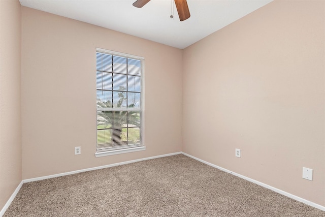 carpeted spare room featuring a ceiling fan and baseboards