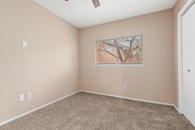 carpeted spare room featuring ceiling fan and baseboards