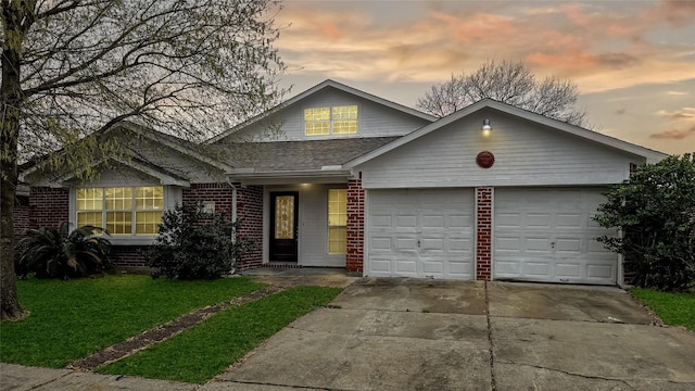 view of front facade featuring a garage, brick siding, a shingled roof, driveway, and a front lawn