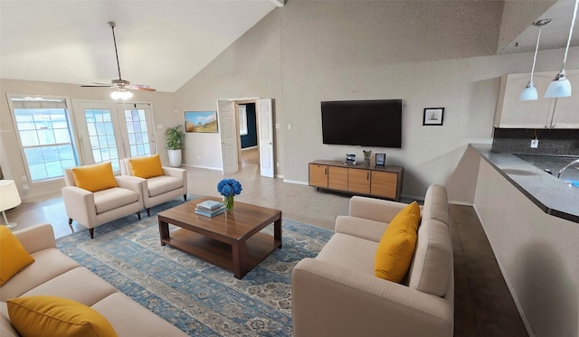 living room with ceiling fan, high vaulted ceiling, and baseboards