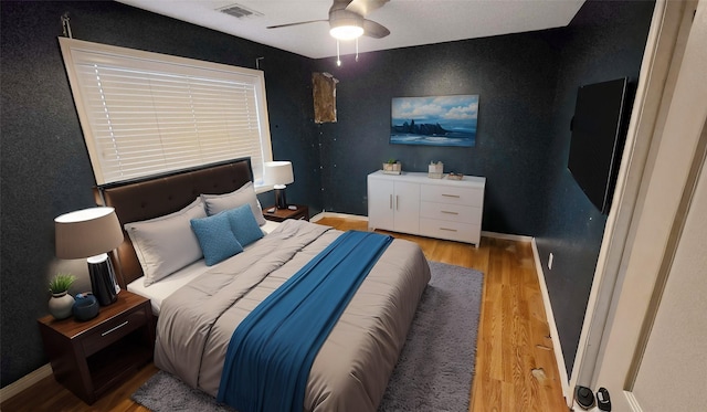 bedroom featuring a ceiling fan, baseboards, visible vents, and light wood finished floors