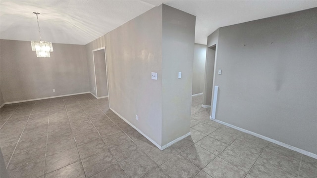 spare room featuring light tile patterned floors, baseboards, and an inviting chandelier