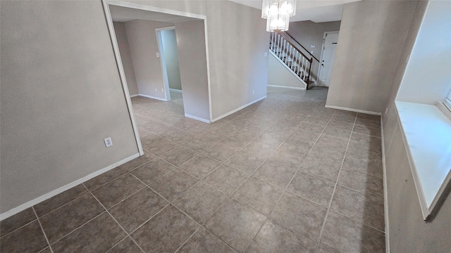 tiled empty room featuring a chandelier, stairway, and baseboards