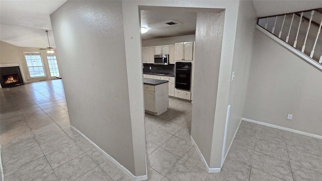 hallway with light tile patterned floors, visible vents, a textured wall, stairway, and baseboards