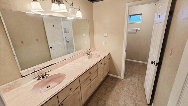 full bathroom featuring baseboards, double vanity, a sink, and tile patterned floors