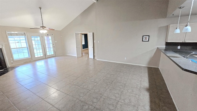 unfurnished living room featuring high vaulted ceiling, baseboards, a ceiling fan, and a high end fireplace