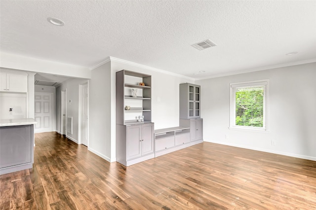 unfurnished living room with dark wood-type flooring, visible vents, crown molding, and a textured ceiling