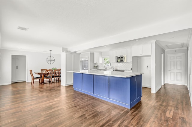 kitchen with decorative light fixtures, visible vents, light countertops, stainless steel microwave, and white cabinets