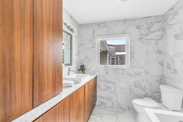 full bathroom with marble finish floor, double vanity, a sink, and toilet