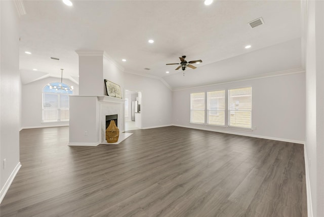 unfurnished living room with ceiling fan with notable chandelier, a premium fireplace, vaulted ceiling, dark wood finished floors, and crown molding