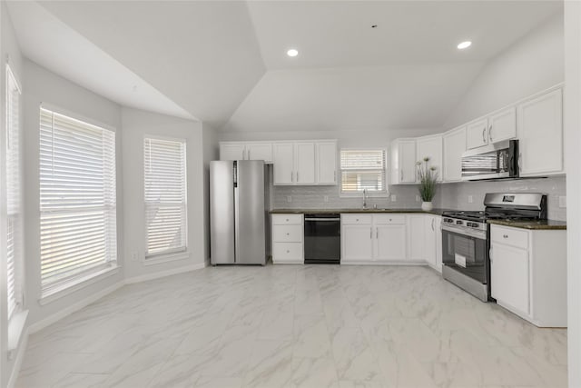 kitchen featuring lofted ceiling, recessed lighting, decorative backsplash, appliances with stainless steel finishes, and white cabinets