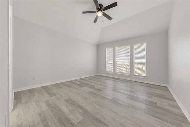 spare room with vaulted ceiling, light wood-type flooring, a ceiling fan, and baseboards