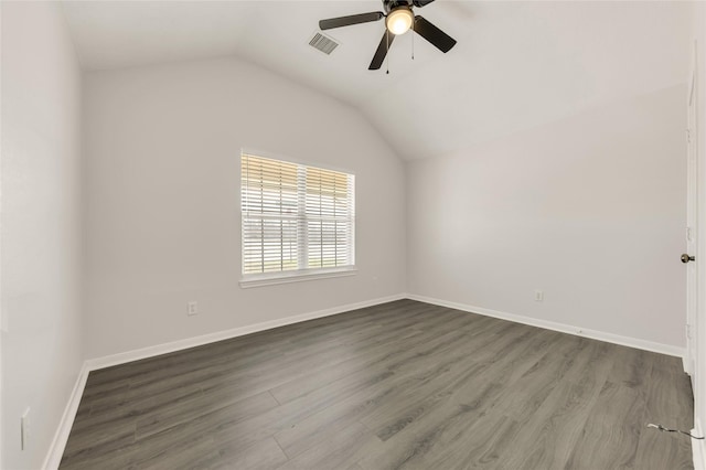 spare room with lofted ceiling, wood finished floors, visible vents, and baseboards