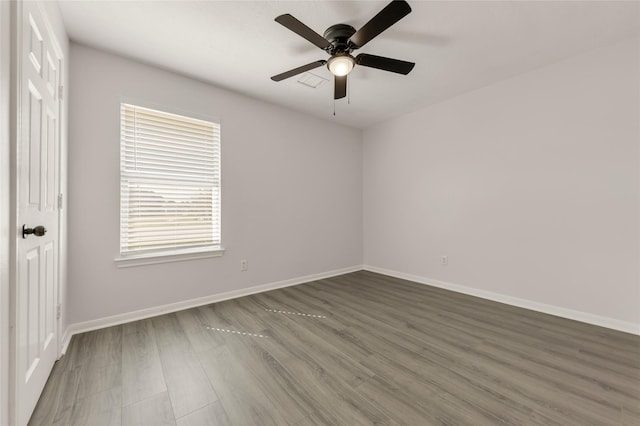 empty room featuring ceiling fan, baseboards, and wood finished floors