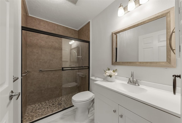 bathroom featuring a textured ceiling, a shower stall, toilet, and vanity