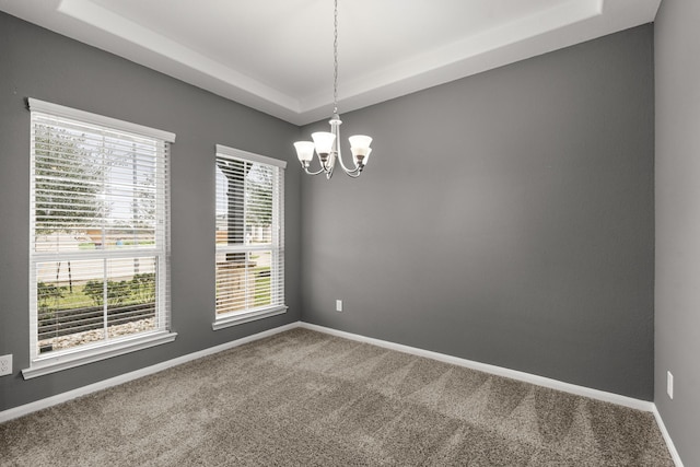 unfurnished room featuring carpet floors, baseboards, a tray ceiling, and a notable chandelier