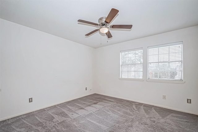 carpeted empty room featuring a ceiling fan and baseboards