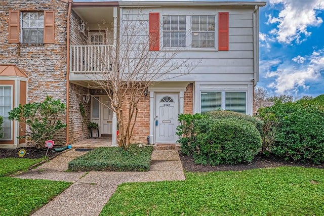 multi unit property with a balcony and brick siding