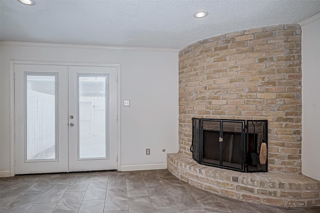 unfurnished living room with ornamental molding, french doors, a textured ceiling, and a fireplace