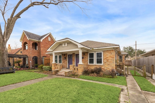 view of front of property featuring a fenced front yard, a gate, a front lawn, a porch, and brick siding