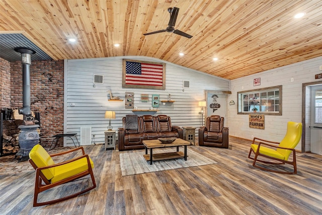 living area featuring lofted ceiling, wooden ceiling, wood finished floors, and a wood stove