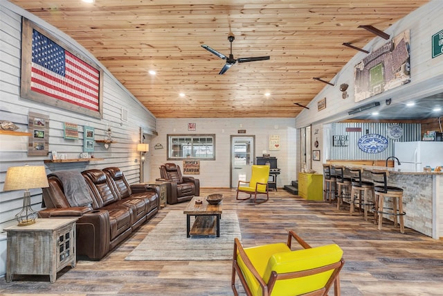 living area with lofted ceiling, ceiling fan, wood finished floors, wooden ceiling, and bar