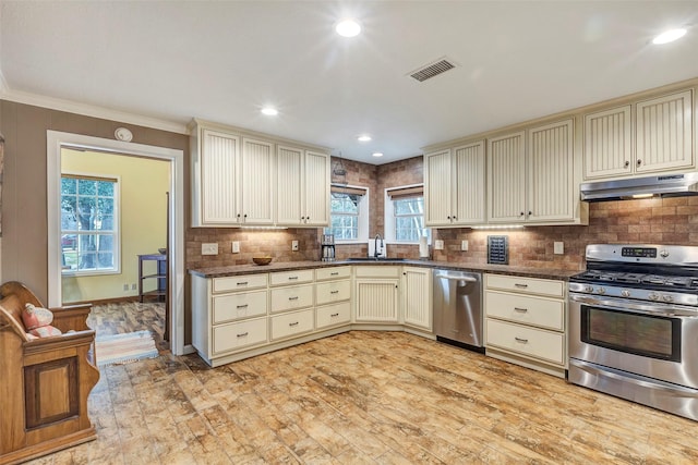 kitchen featuring appliances with stainless steel finishes, cream cabinetry, visible vents, and under cabinet range hood