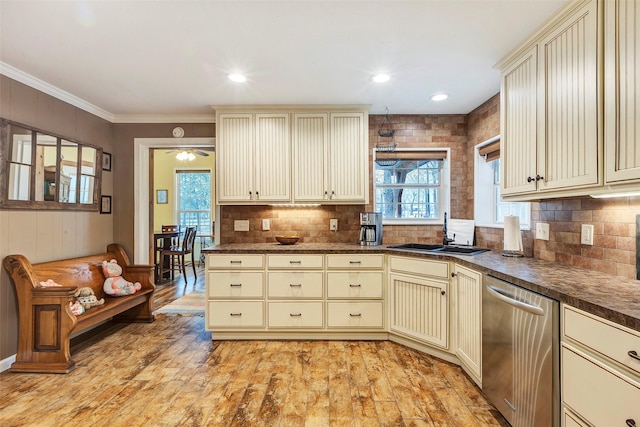 kitchen featuring stainless steel dishwasher, dark countertops, and cream cabinets