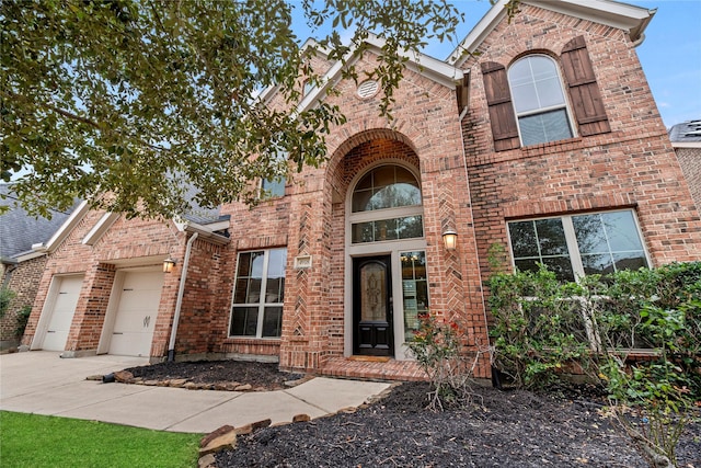 traditional-style home featuring a garage, concrete driveway, and brick siding