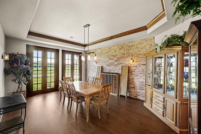 dining area featuring brick wall, visible vents, french doors, a tray ceiling, and dark wood finished floors