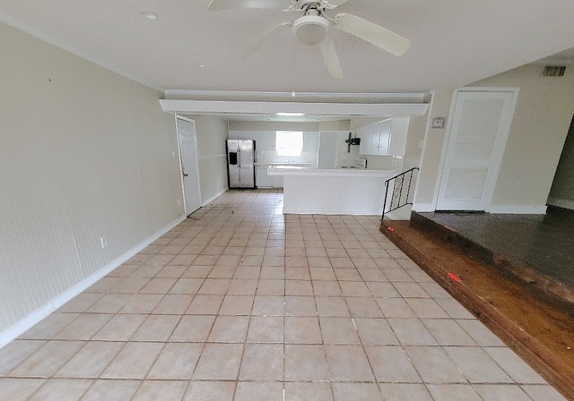 unfurnished living room with a ceiling fan, visible vents, baseboards, and light tile patterned floors