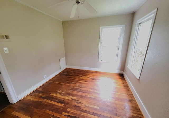 unfurnished room featuring a healthy amount of sunlight, dark wood-style floors, ceiling fan, and baseboards