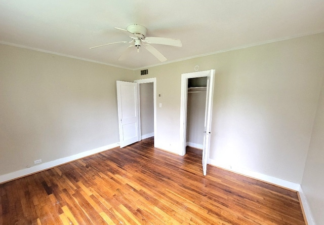 unfurnished bedroom with crown molding, a closet, visible vents, wood finished floors, and baseboards