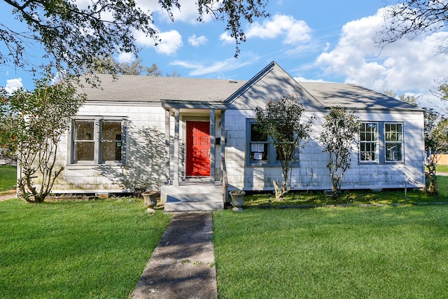 ranch-style home featuring a shingled roof and a front yard