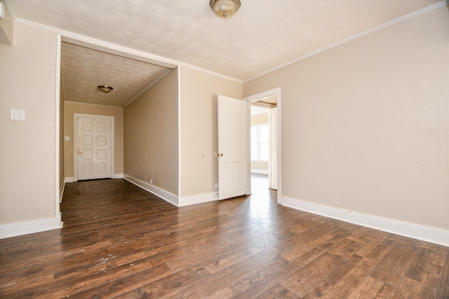 spare room featuring ornamental molding, baseboards, and wood finished floors