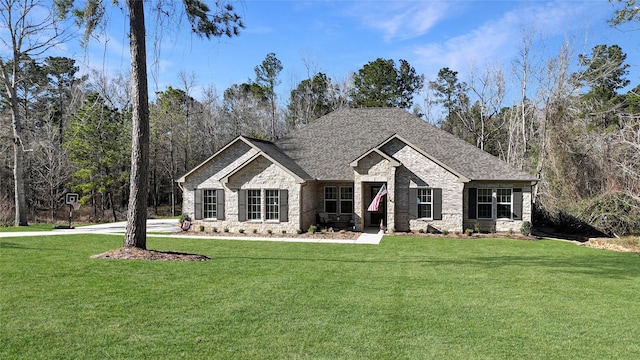 view of front facade with a front yard, stone siding, and roof with shingles