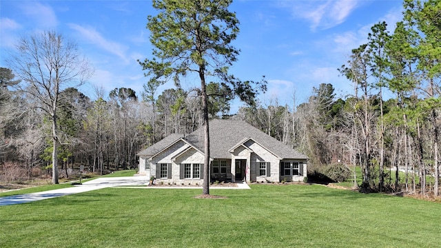 view of front of property featuring stone siding, a shingled roof, a front lawn, and a view of trees