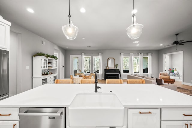 kitchen featuring open floor plan, light countertops, a sink, and stainless steel dishwasher