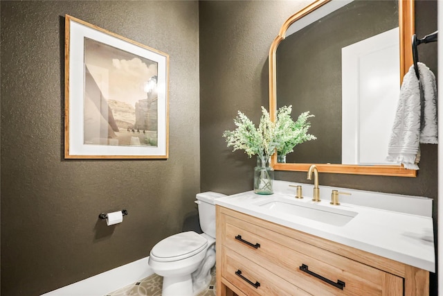 bathroom featuring a textured wall, vanity, and toilet