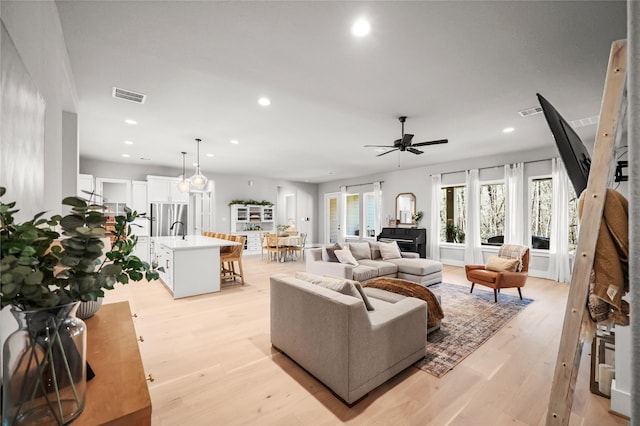 living area featuring a ceiling fan, light wood-type flooring, visible vents, and recessed lighting