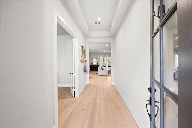 hall featuring light wood-type flooring, visible vents, and baseboards