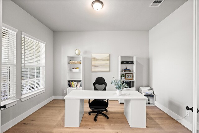 office space featuring light wood-type flooring, visible vents, and baseboards