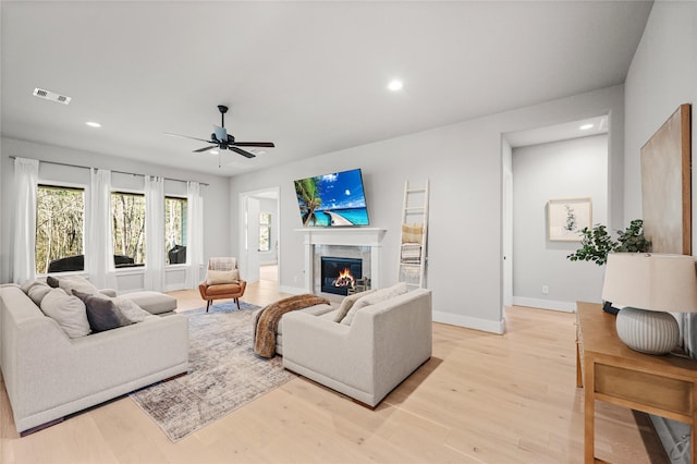 living room with light wood finished floors, a glass covered fireplace, visible vents, and recessed lighting