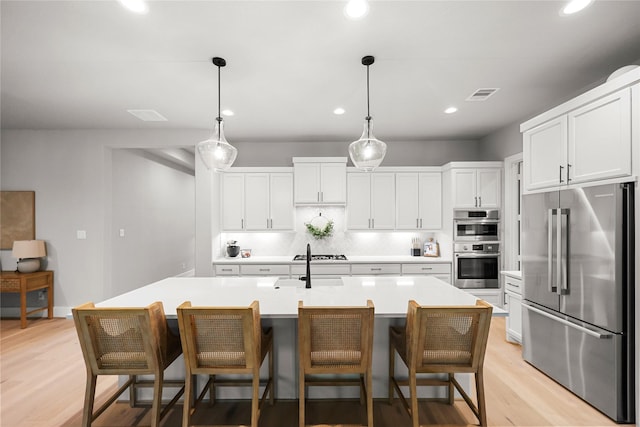 kitchen with visible vents, light countertops, appliances with stainless steel finishes, light wood-type flooring, and backsplash