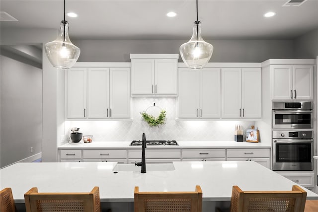 kitchen featuring white cabinetry, tasteful backsplash, appliances with stainless steel finishes, and a kitchen breakfast bar